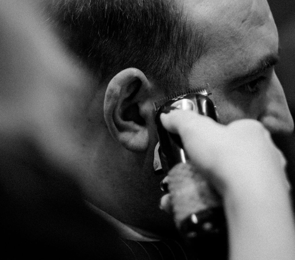 A detailed black and white image of a haircut being done with a clipper.